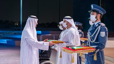 Sheikh Hamad bin Mohammed Al Sharqi, Ruler of Fujairah, presents a medal to a family member of a hero who passed away this year, during the Commemoration Day ceremony. Photo: Mohamed Al Hammadi / Ministry of Presidential Affairs