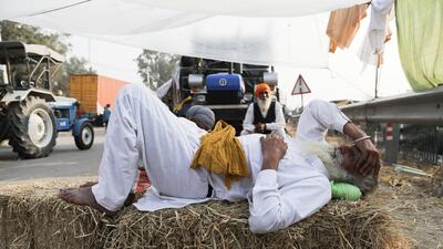 A farmer rests on a stack of hay at a site of a protest against the newly passed farm bills at Singhu border near Delhi, India. Reuters