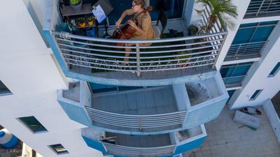 This picture taken on March 23, 2020 shows Uruguayan cellist Karina Nunez playing on the balcony of her apartment in Panama City, during the mandatory isolation from 5pm to 5am as a preventive measure against the spread of the COVID-19 novel coronavirus. / AFP / Luis ACOSTA