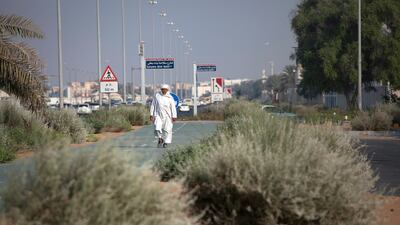 A pedestrian walks along a green stretch in Abu Dhabi. The National