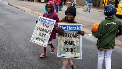 Children hold two posters as they wait for the start of the parade of the South African Rugby World Cup winner with their Web Ellis Trophy, in Kwazakhele. AFP