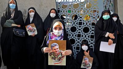 Iranian women lift portraits of Col Hassan Sayad Khodai during his funeral in Tehran. AFP