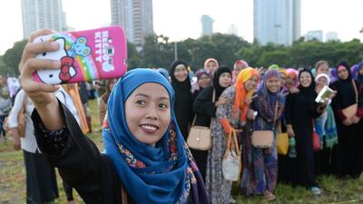 Muslim women pose for a selfie after attending prayers at a park in Manila. AFP