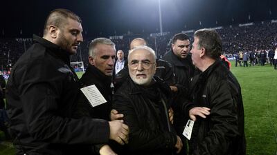 PAOK president Ivan Savvidis, centre, is escorted out after taking to the pitch carrying a handgun in his waistband in Thessaloniki. Sakis Mitrolidis / AFP