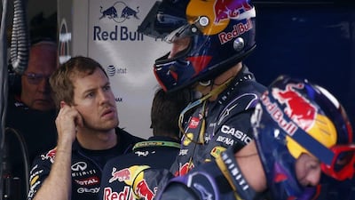 Red Bull Formula One team driver Sebastian Vettel, left, of Germany watches a television screen after retiring from the race during the Formula One Australian Grand Prix in Melbourne on March 16, 2014. AFP PHOTO / David Gray