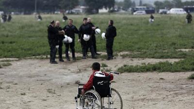 A refugee boy on a wheelchair passes in front of riot police. In Idomeni, most have been living in small camping tents pitched in fields and along railway tracks, while aid agencies have set up large marquee-style tents to help house people Yannis Kolesidis / Reuters