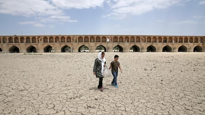 A woman and a boy walk on the dried up riverbed of the Zayandeh Roud river that no longer runs under the 400-year-old Si-o-seh Pol bridge, named for its 33 arches, in Isfahan, Iran, on July 10, 2018. AP Photo