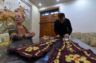Iraqi priest Ammar Yaqo looks on as Karjiya Baqtar embroiders a prayer shawl using golden thread to gift to Pope Francis. AFP