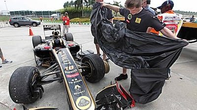 Team mechanics, above, prepare a cover for Vitaly Petrov’s damaged Lotus-Renault outside the pit lane after the first practice in Malaysia, which has not gone as well as the season-opener in Australia for the team.