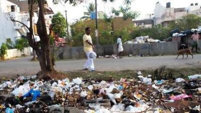 A resident throws a bag of rubbish into a roadside dump in Bengaluru. Amirtharaj Stephen for The National