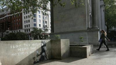 A woman walks nearby an artwork which appears to be by street artist Banksy. PA via AP