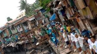 Workers from the Metropolitan Manila Development Authority demolish shanties along an open canal in Manila.