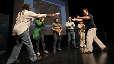 David Crane, left, and Ernesto Verdugo, right, hand out a prize of restaurant vouchers during a game of "The Price Is Right" at YouLearnTwitFace, an online marketing conference at the Dubai Community Theatre and Arts Centre in the Mall of the Emirates last weekend.