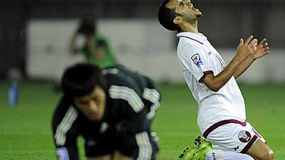 Qatar's midfielder Mohammed Abdulraab Alyazidi, right, reacts after missing the chance to score as Japan's goalkeeper Seigo Narazaki lies on the grass.