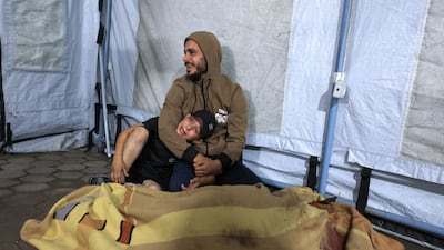 A man and a child mourn by the covered body of a Palestinian killed in an Israeli air strike, at Al Ahli Arab Hospital in Gaza city on Wednesday. Reuters