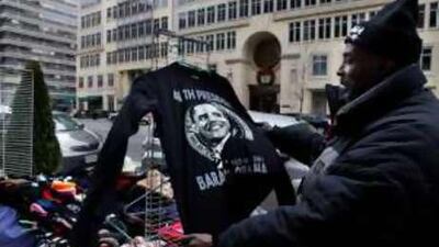 Cornelius Williams displays a T-shirt bearing an image of Barack Obama, the president-elect, at his vendor stand in Washington.