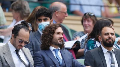 Fitness coach Joe Wicks, centre, sits as Tunisia's Ons Jabeur and Spain's Garbine Muguruza play their women's singles third round match on the fifth day of the 2021 Wimbledon Championships.