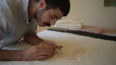 Fadi Al Melhem uses a wooden block to apply a pattern to blank textile. Finbar Anderson / The National
