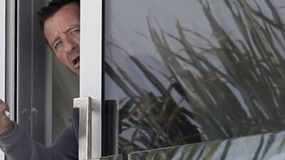Phil Rudd, drummer for the rock band AC/DC, gestures from a window at his house in Tauranga, New Zealand on November 6. John Borren / New Zealand Herald / AP Photo