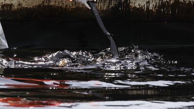 A worker uses a shovel to row through leaked oil on the San Juan river in Cadereyta. Daniel Becerril / Reuters