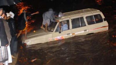 Yemenis ready to rescue a foreign tourist in a vehicle stranded in flood waters in the old sector of the Yemeni capital Sanaa.