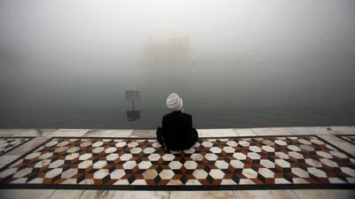 A Sikh man sits near the sacred pond of the Golden Temple, the holiest of Sikh shrines in a foggy Amritsar, India. Raminder Pal Singh / EPA