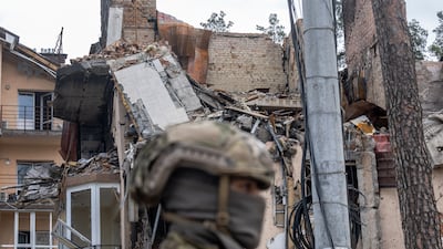 A Ukrainian soldier stands guard at a damaged residential building. Getty Images