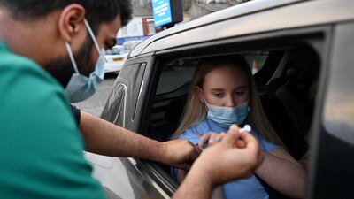 A health worker inoculates a woman at a drive-through NHS vaccination centre outside Ewood Park stadium in Blackburn. AFP