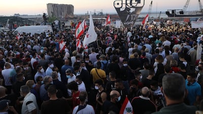 People wave Lebanese flags and chant to mark the first anniversary of anti-government protests with a background of the destroyed silos at Beirut port. Getty Images