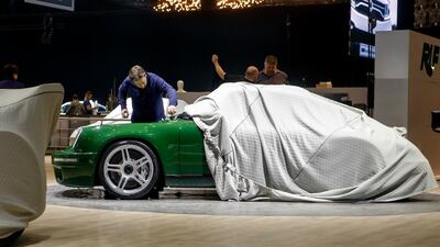 A representative of the RUF booth cleans a car on the Porsche restoration company's stand. Keystone via AP