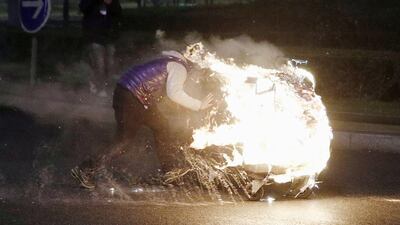 A man sets fire to rubbish in a shopping trolley during protests in Bobigny, a suburb of Paris. Yoan Valat / EPA