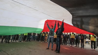 Protesters stand under a giant Palestinian flag during a demonstration against Trump's Middle East peace proposal in Khan Yunis in the southern Gaza Strip. AFP