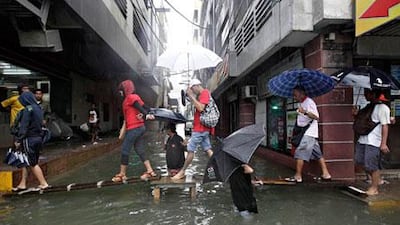 Filipinos in Metro Manila walk along planks of wood to keep out of heavy flood waters that the paralysed the Philippine capital. Rolex dela Pena / EPA