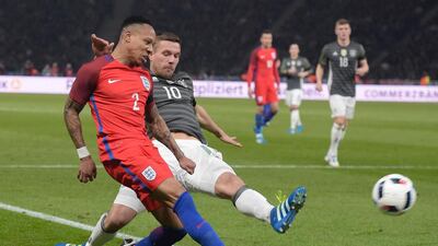 England’s defender Nathaniel Clyne (L) and Germany’s midfielder Lukas Podolski vie for the ball during the friendly football match Germany vs England at the Olympic Stadium in Berlin on March 26, 2016. / AFP / TOBIAS SCHWARZ