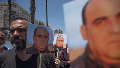 Angry demonstrators carry pictures of Nizar Banat, an outspoken critic of the Palestinian Authority, and chant anti-PA slogans during a rally protesting his death, in the West Bank city of Ramallah. AP