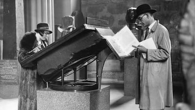 Visitors reading information concerning the Rosetta Stone, from the top of the stone itself, in the Egyptian Gallery in 1932