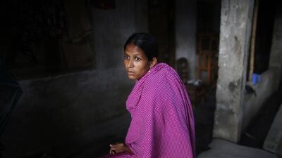 Salma, who was rescued from the rubble of the collapsed Rana Plaza building, sits inside her slum house in Savar. Salma, who is unable to work due to a spinal injury sustained from the accident last year, says she has not received any compensation.