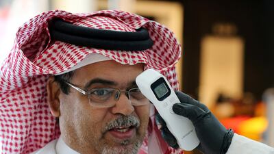 A security guard checks the temperature of a man at a shopping mall in Riyadh, Saudi Arabia. Reuters