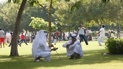 Two Emirati Al Ayala performers sit in the shade at Zabeel Park before entertaining people who have gathered in the park to celebrate Eid. Mike Young / The National
