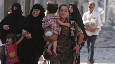 A Syria Democratic Forces fighter helps civilians who were evacuated by the SDF from an ISIL-controlled neighbourhood of Manbij, in Aleppo. Rodi Said / Reuters