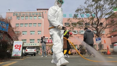 A worker wearing protective gear sprays disinfectant against the coronavirus in front of the Daenam Hospital in Cheongdo, South Korea. Lim Hwa-young/Yonhap via AP