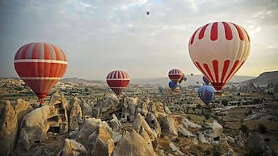 Tourists enjoy hot-air balloon rides over the spectacular soft rock formations near Goreme in Cappadocia. The rocks are volcanic deposits that have eroded over the centuries and were carved out to form vast underground cities.