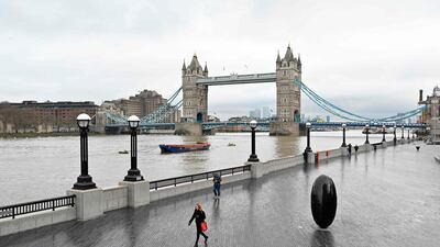 People walk along a very quiet bank of the River Thames in London. AFP