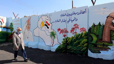 A man walks past a mural depicting the visit of Pope Francis on the concrete walls surrounding the Our Lady of Salvation Church in Baghdad. EPA