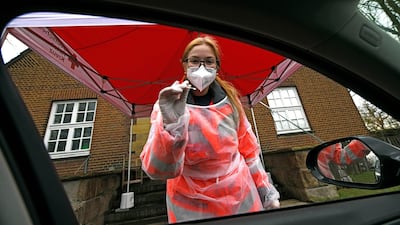 A Red Cross worker in protective clothes prepares to administer a Covid-19 rapid test. AP