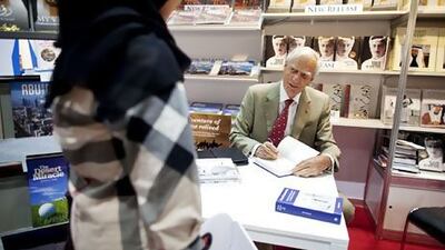 Author David Heard of the UK signs a copy of his book, From Pearls to Oil, during the Abu Dhabi International Book Fair. Christopher Pike / The National