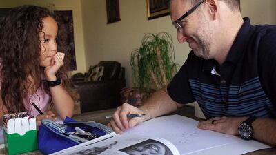 American teacher Scott Baldwin and his daughter Sophia, 7, draw different faces that show various emotions during an art session at their home in Abu Dhabi. Delores Johnson / The National