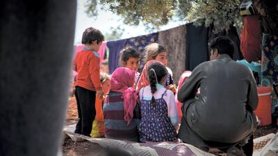 Mustafa sitting with his sons and other children who fled from the village with their families.