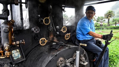 Train driver Hari Chettri sits in the engine of Darjeeling Himalayan Railway steam train as it leaves Batasia Loop.