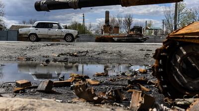 A shell-damaged car passes destroyed armoured vehicles in Kolychivka village in Ukraine. EPA